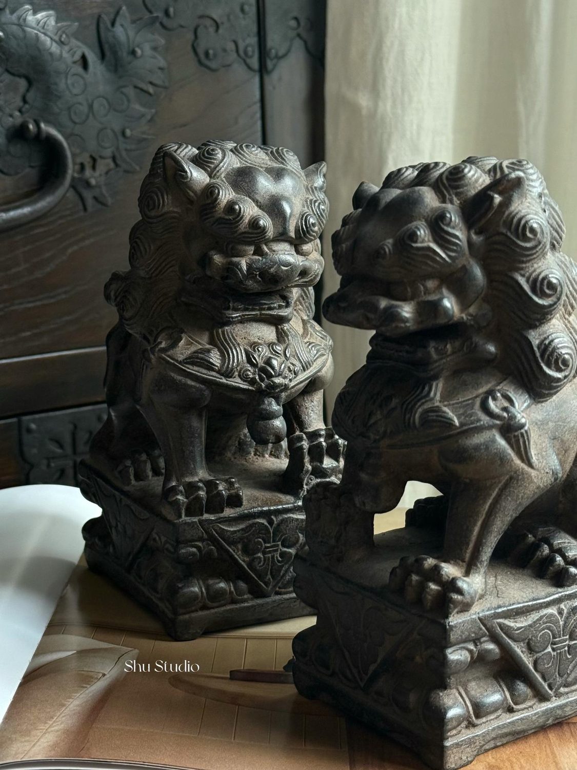 A carved guardian lion resting on an open book.