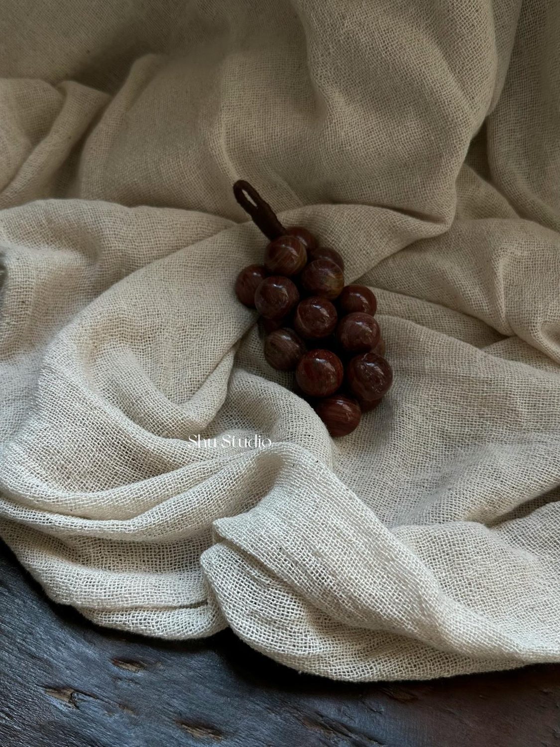Carved stone grapes resting on a lacquer tray in low light.
