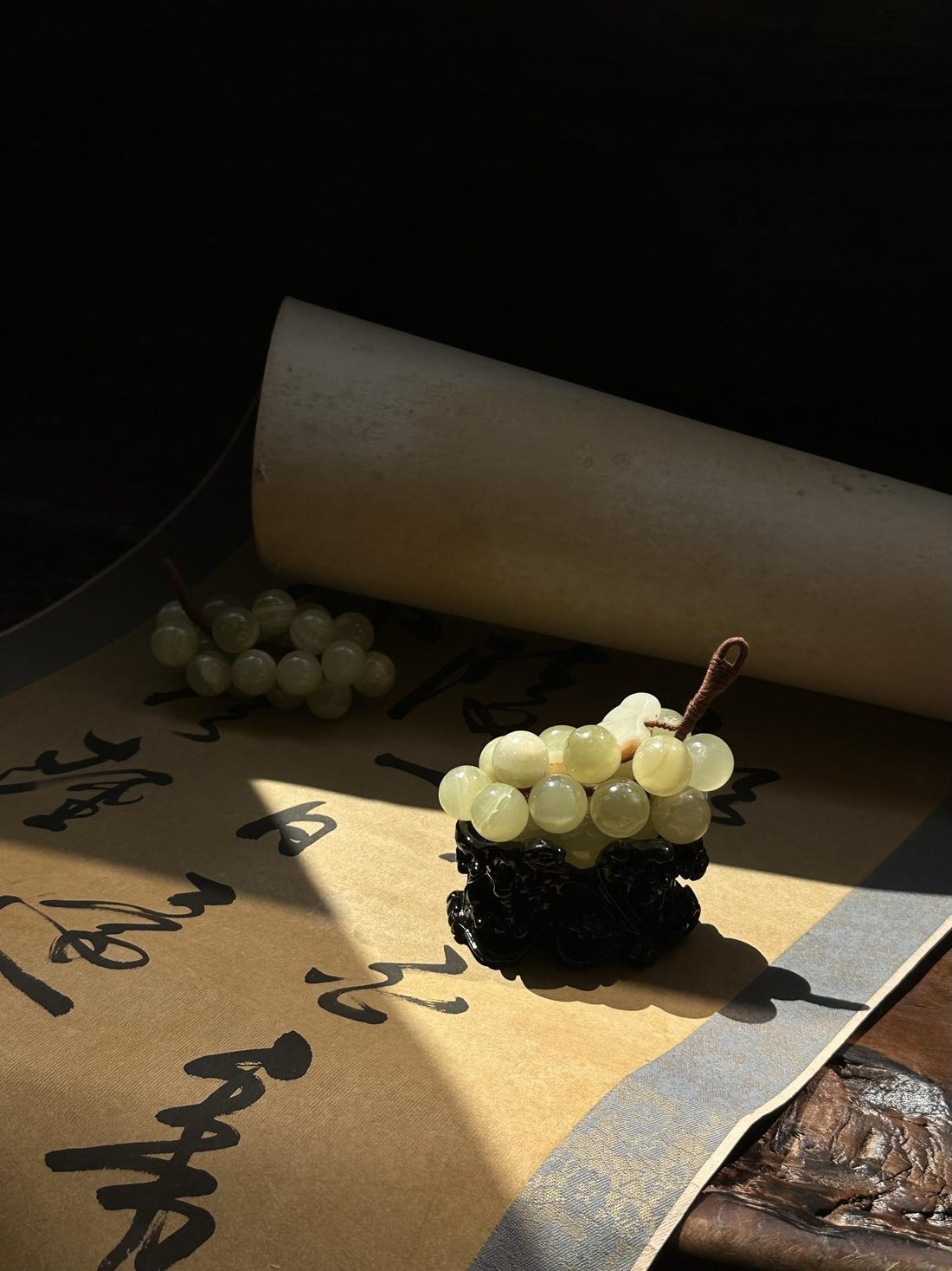Green stone grapes on a carved stand, lit by a low sun.