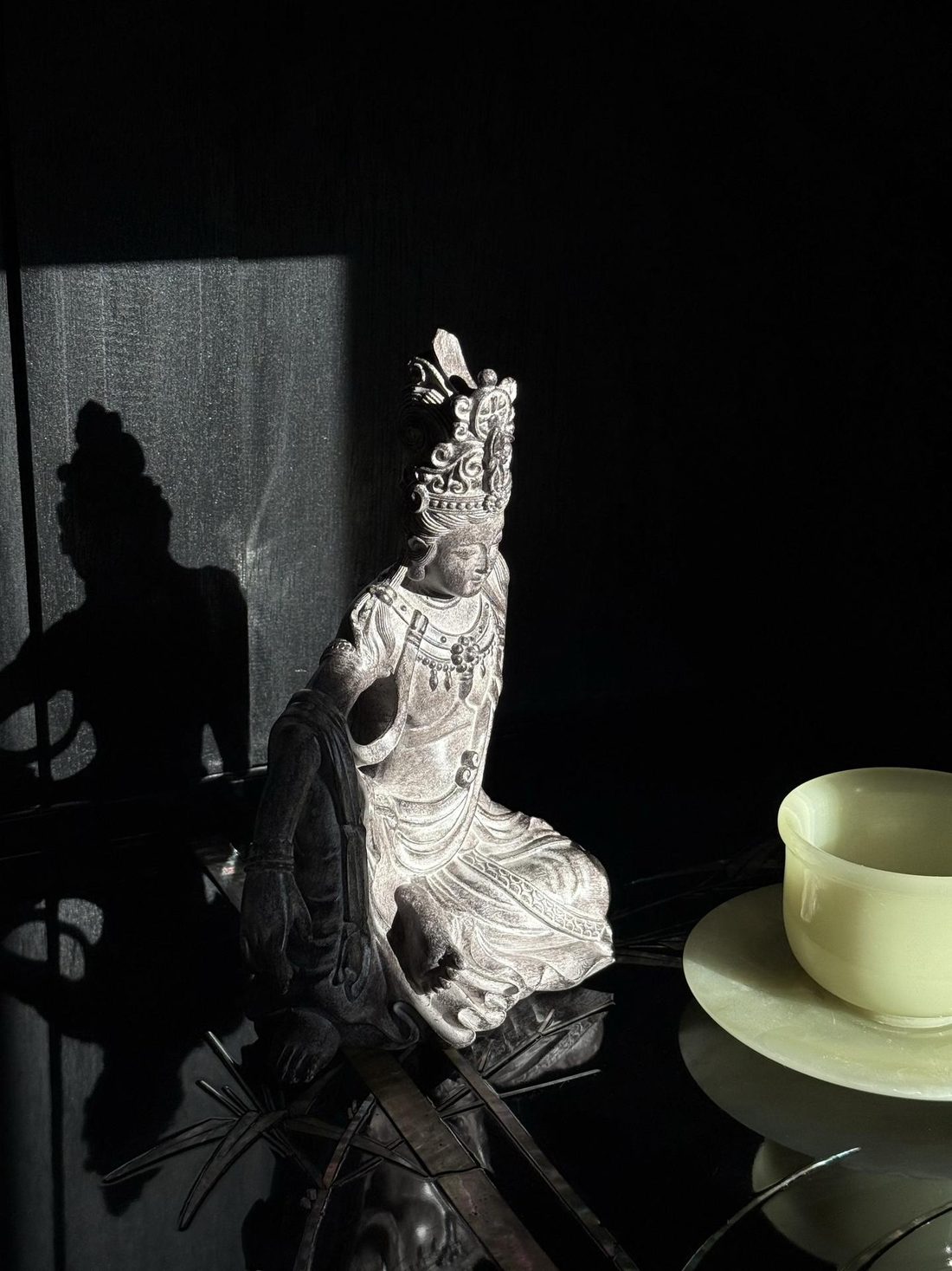 The stone bodhisattva seen from the side in dim light.